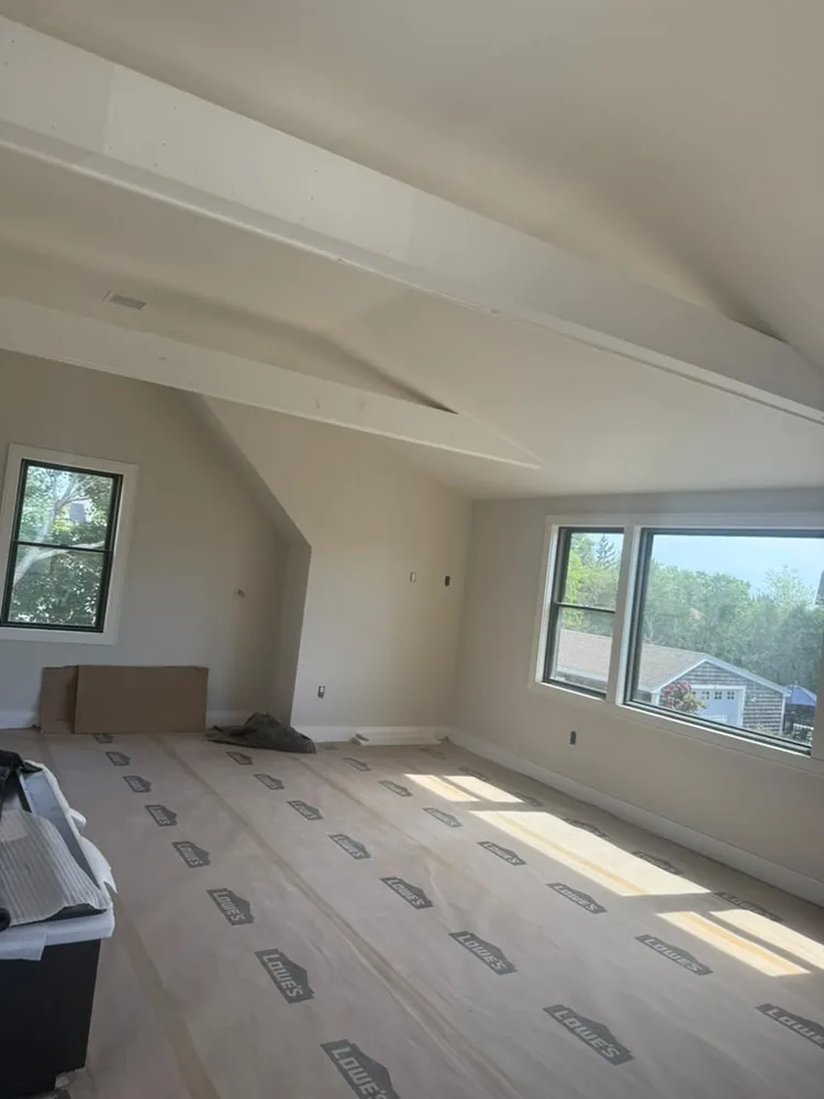 Attic room with white walls and the floor covered for finishing work