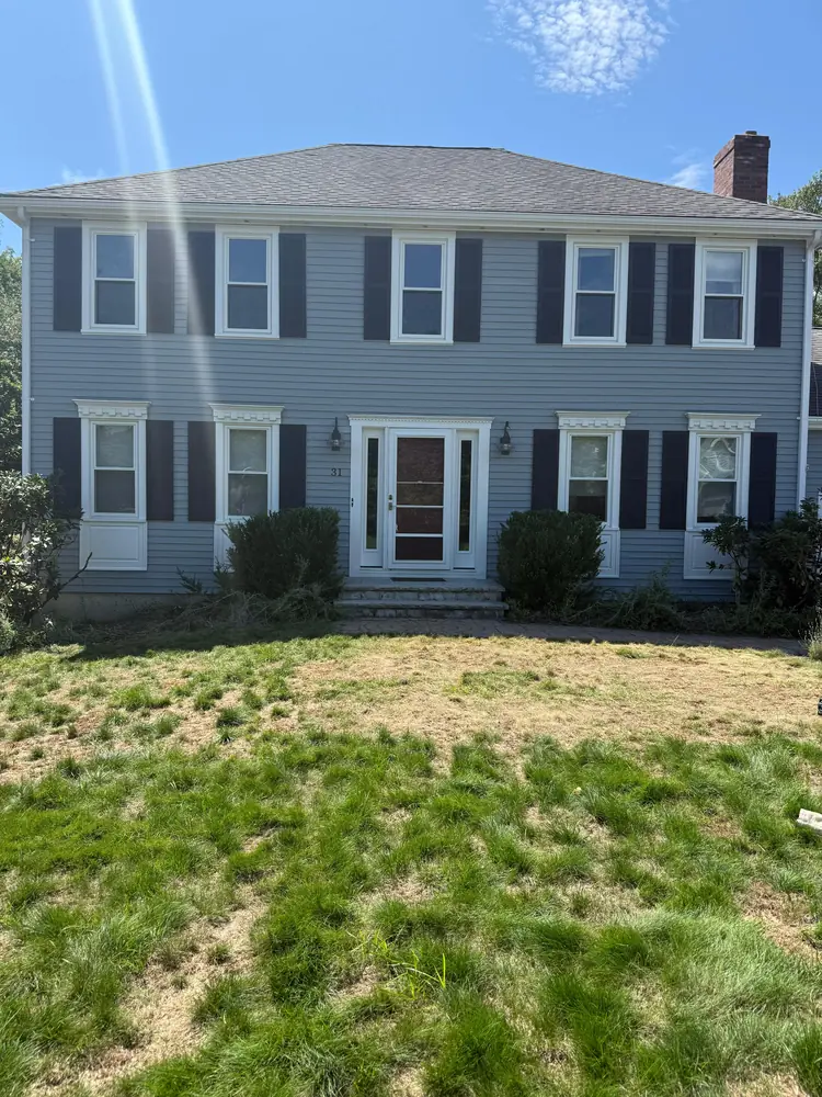 Two story colonial in soft blue with white trim and dark shutters