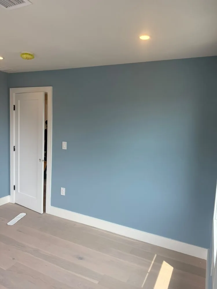 Bedroom painted a soft blue gray with white trim and a new door