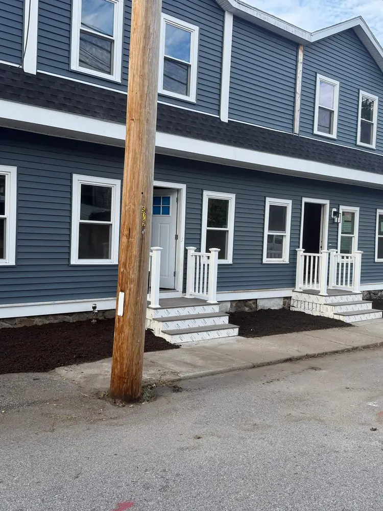 Blue multi unit building with white trim and two new front porches