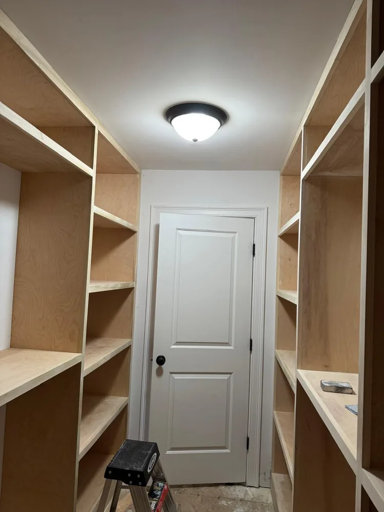 Walk in closet with custom built in shelving framing the doorway