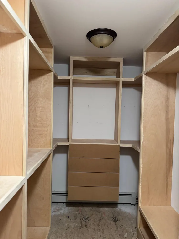 Custom closet build with open shelving above a bank of drawers
