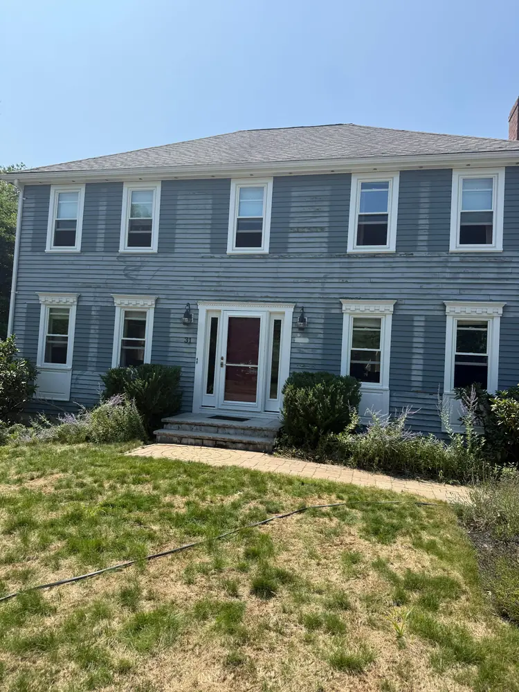 Colonial with fresh white window trim and a deep red front door