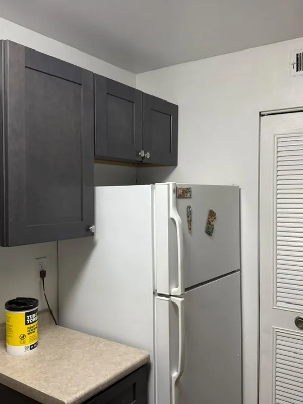 Kitchen with dark shaker cabinets and a white refrigerator