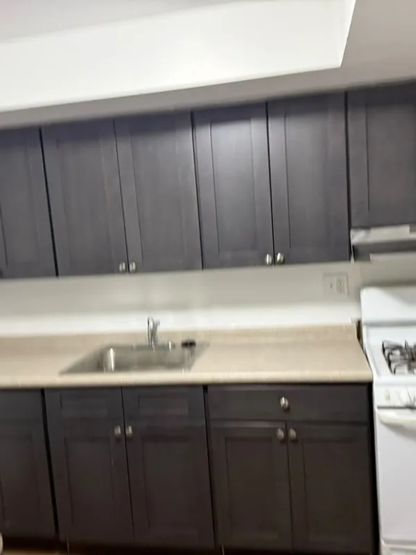 Kitchen with dark cabinets, a beige counter and a white gas stove