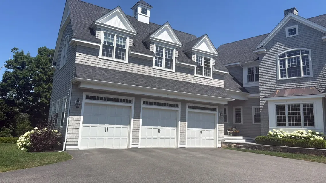 House with three dormers over a triple garage after an exterior repaint
