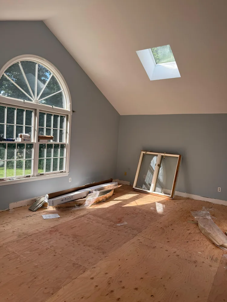 Empty room with gray walls, an arched window and a skylight, ready for flooring