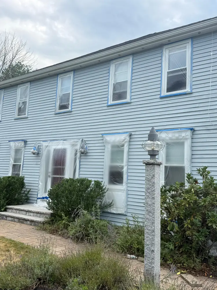 Light blue house with the trim masked off while exterior work is under way