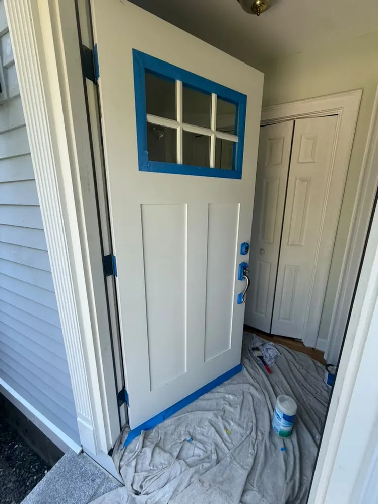 Front door taped off for painting, with drop cloths on the floor