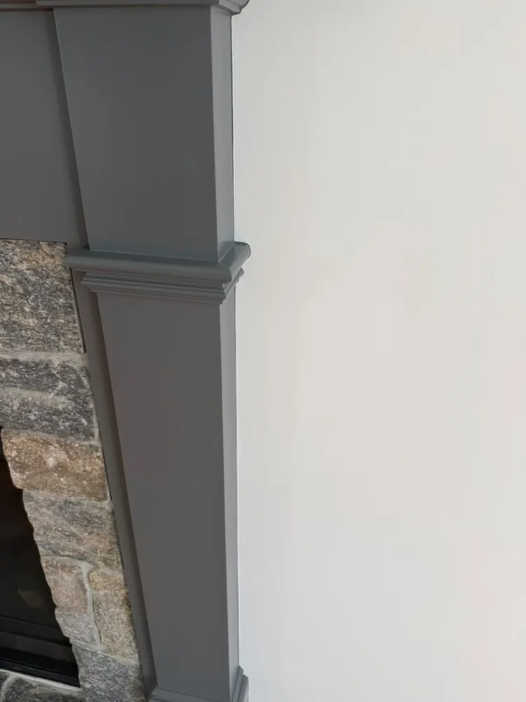 Gray painted column beside a stone wall, with a clean edge on the cream wall