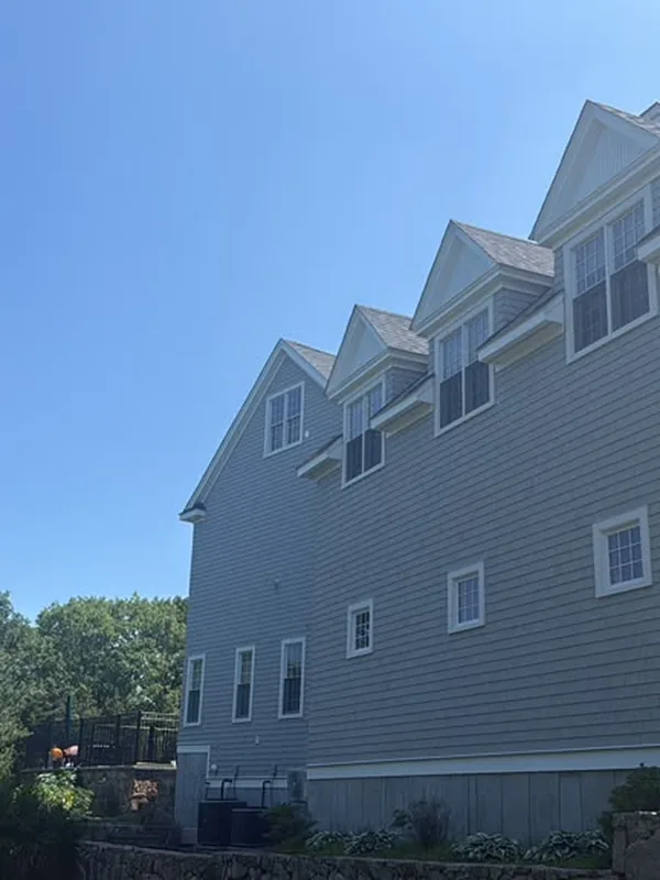 Side of a gray shingle home with three shed dormers and white trim