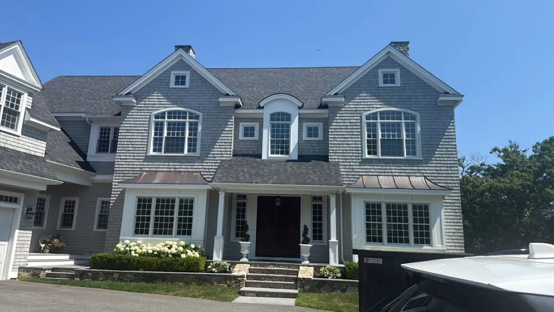 Wide gray shingle home with white trim after a full exterior repaint