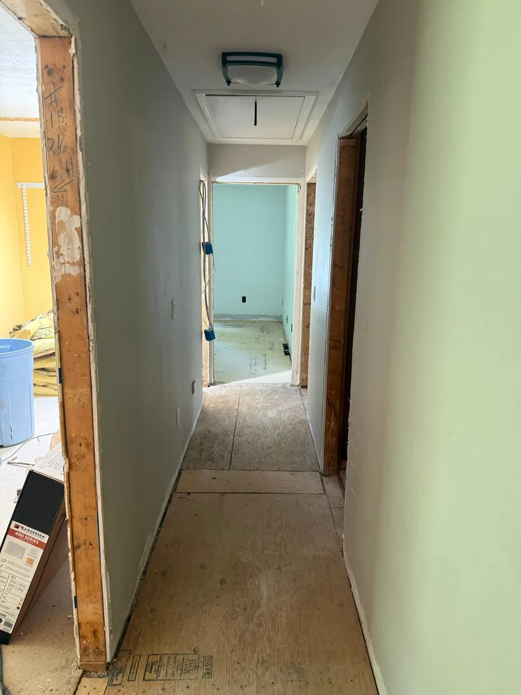 Hallway with the framing exposed and the subfloor open during a remodel
