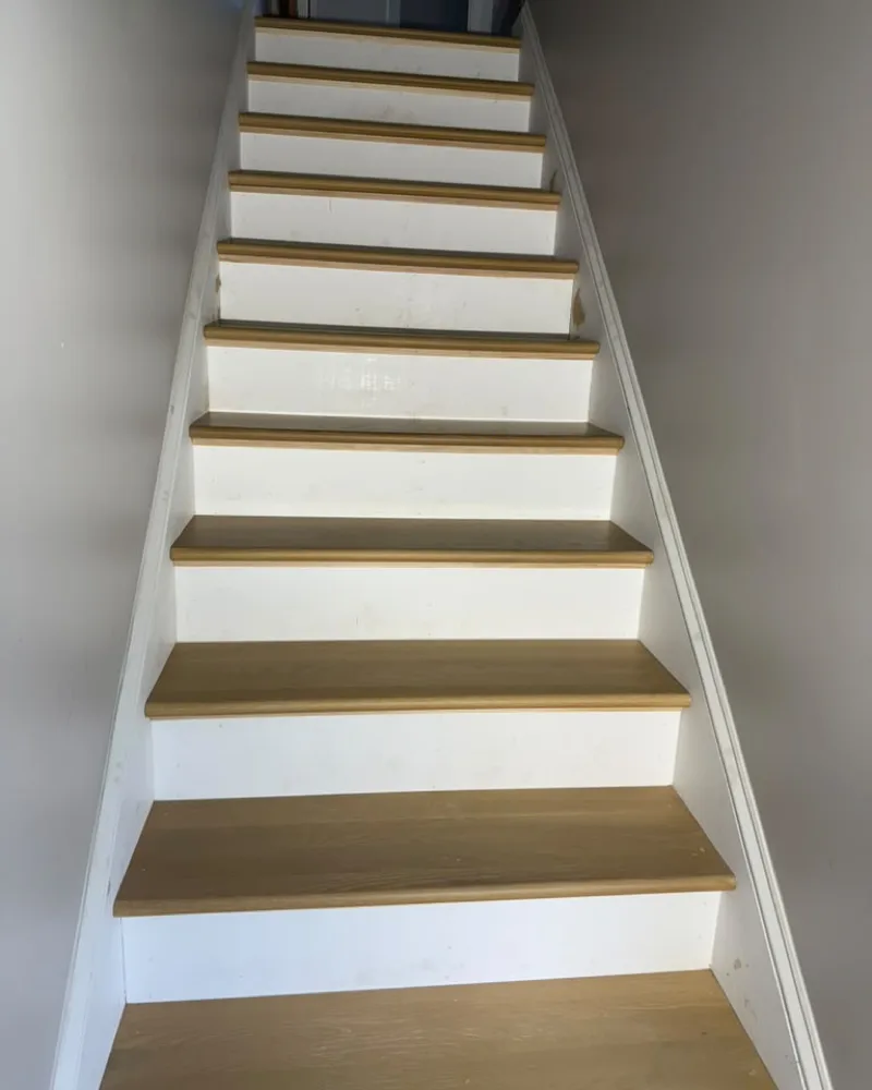 New staircase with oak treads and white risers, built and finished during a home renovation