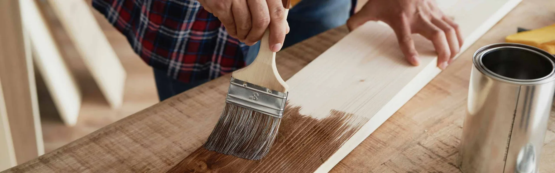 Close up of a brush laying a smooth finish onto wood trim during an interior job