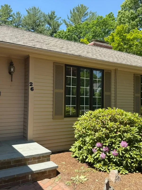 Entry of a tan ranch house with black framed windows