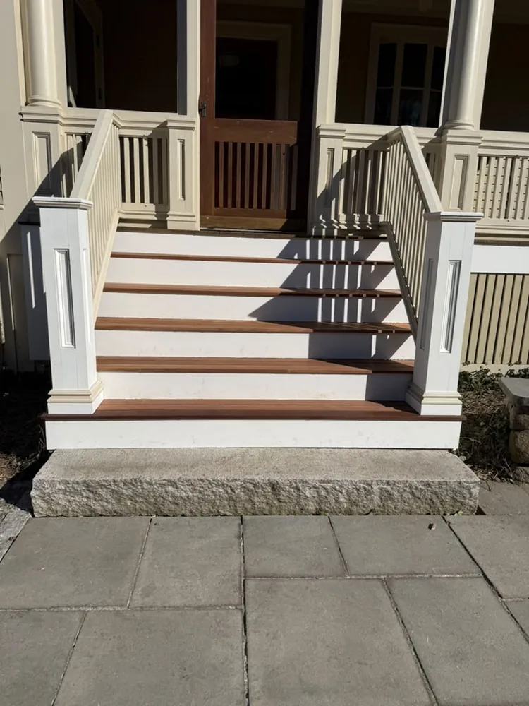 Rebuilt porch stairs with stained treads and white posts, seen from the side