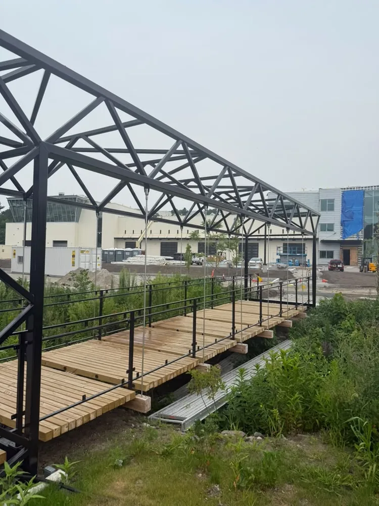 Steel truss pedestrian bridge with new wood decking on a commercial site