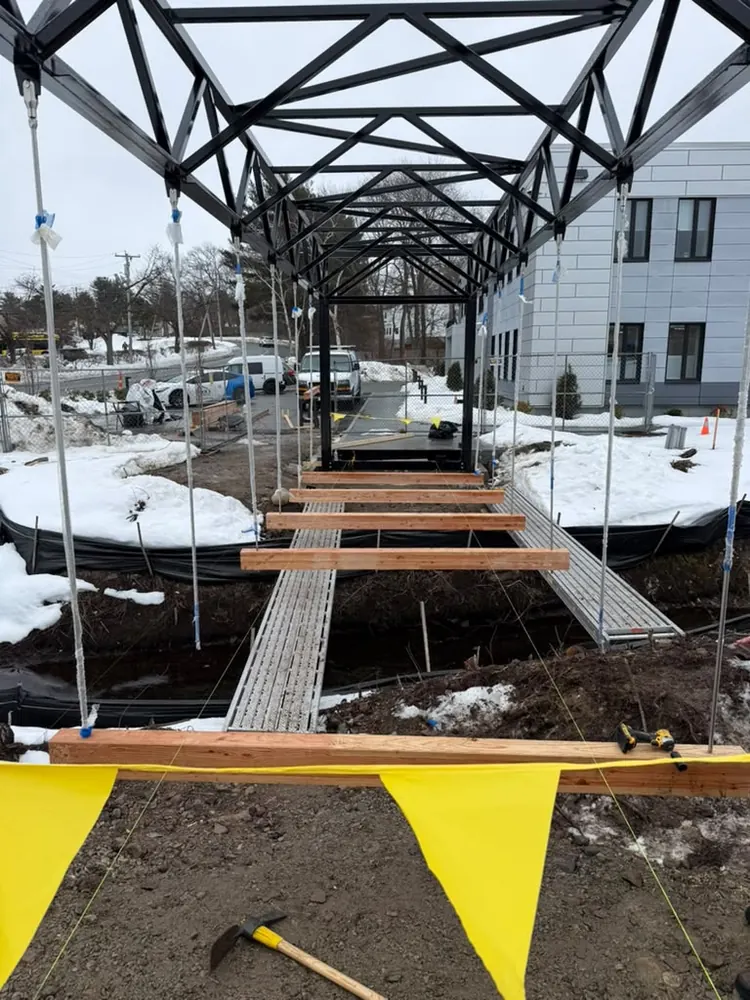 Steel truss bridge under construction in winter, with caution flags