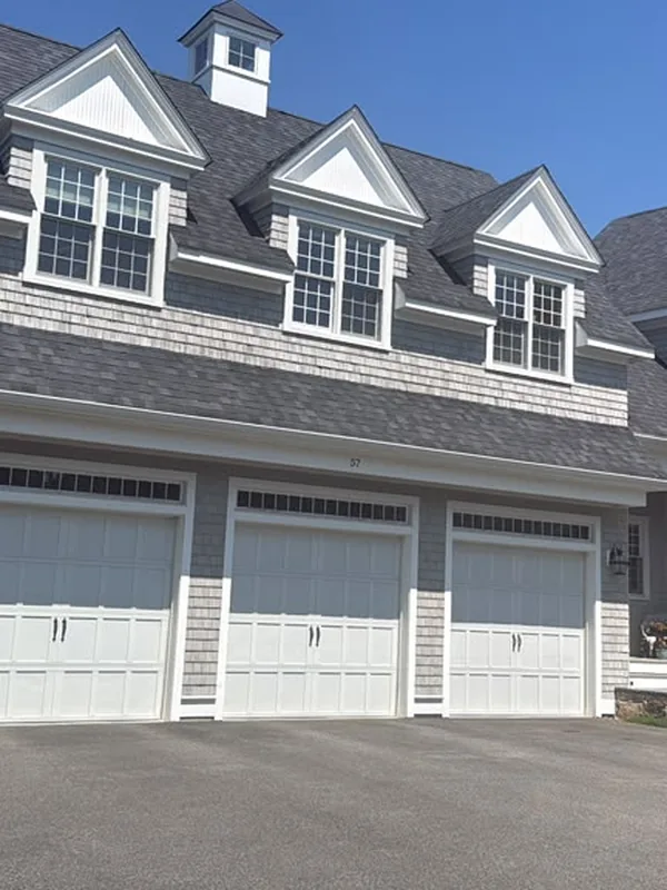 Gray shingle home with dormers above a triple garage