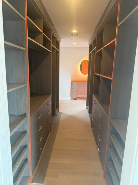 Custom walk in closet with dark built in shelving and drawers