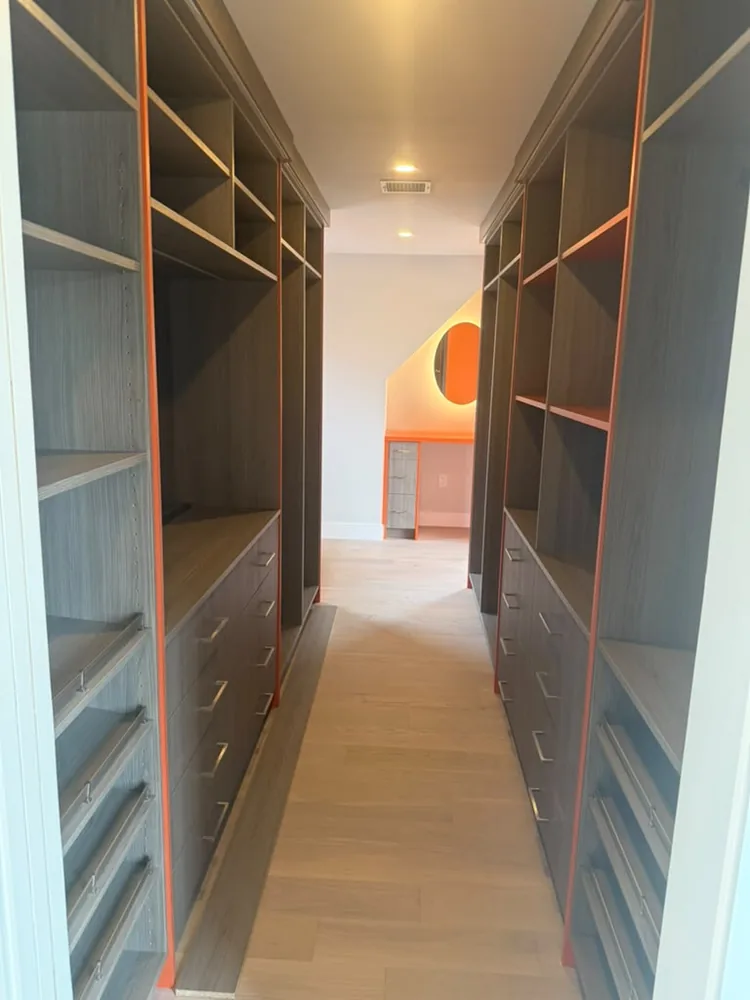 Walk in closet with dark built in shelving and a long bank of drawers