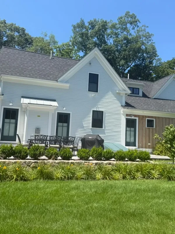 White farmhouse with a covered side porch and fresh landscaping