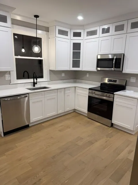 Finished kitchen with white shaker cabinets, quartz counters and new appliances