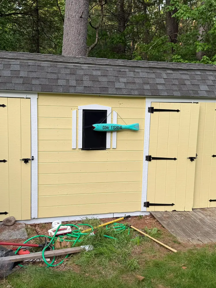Backyard shed after painting, in soft yellow with white trim and black hardware